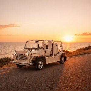 Moke électrique décapotable sur une route côtière au coucher du soleil - SUNCAR France