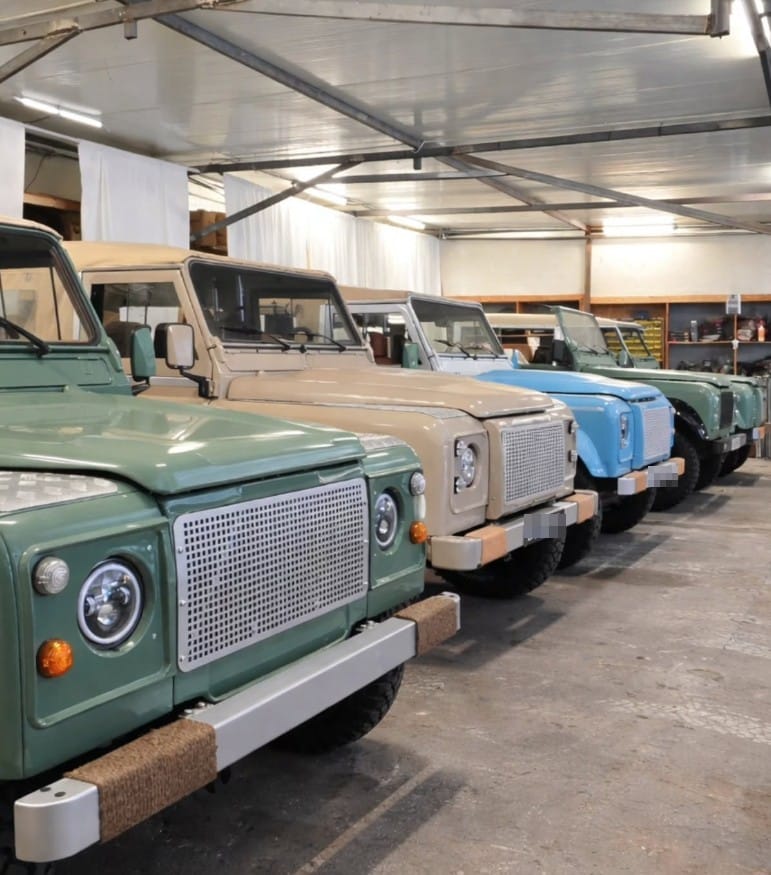 Collection de Land Rover Defender restaurés par SUNCAR alignés dans l'atelier