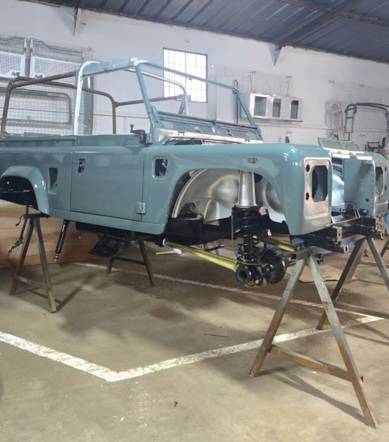 Caisse de Land Rover Defender vert d'eau sur chandelles en atelier pendant sa restauration