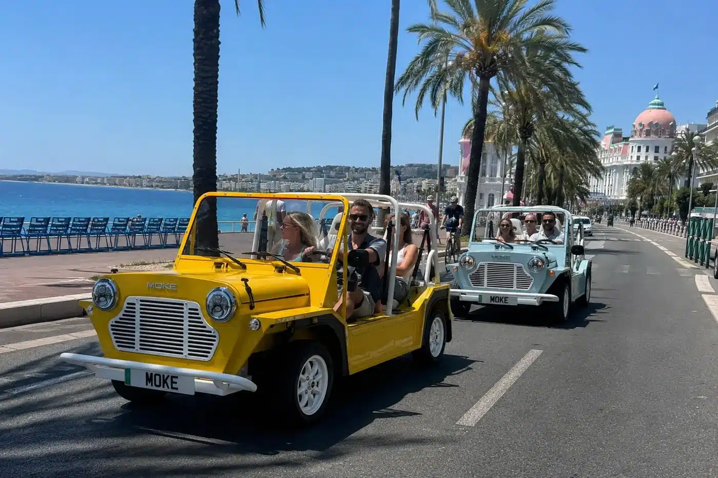 Deux Moke électriques, jaune et bleue, sur la Promenade des Anglais à Nice devant l'hôtel Negresco