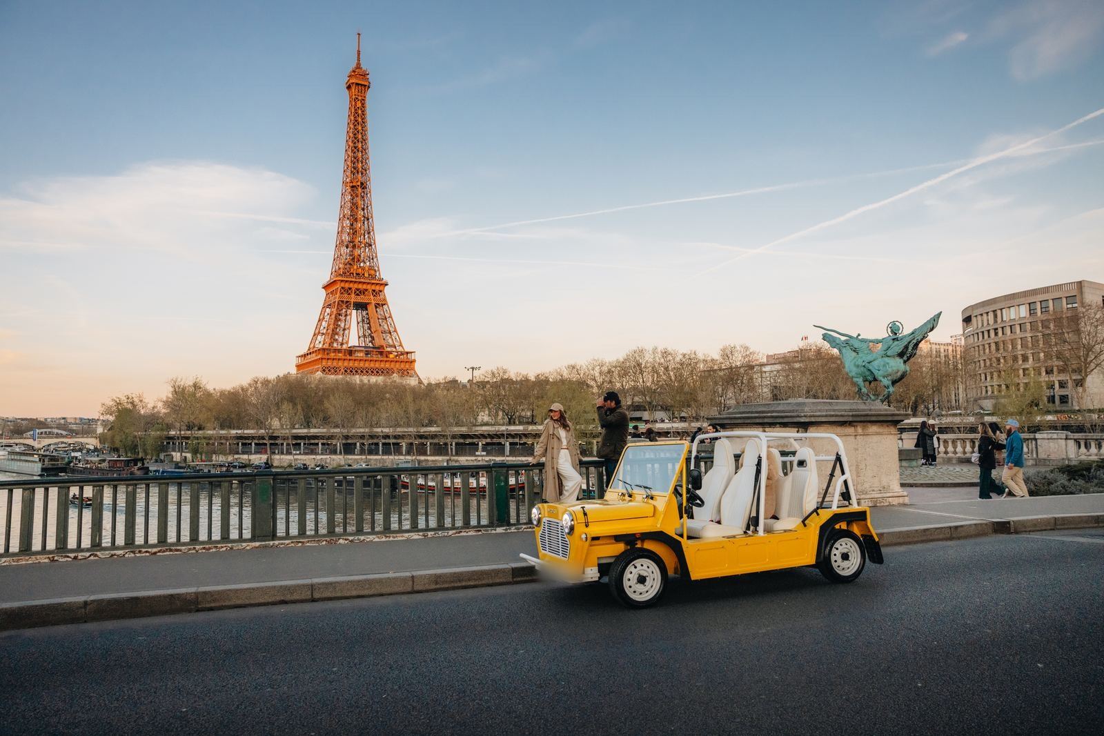 Moke électrique jaune devant la tour Eiffel à Paris